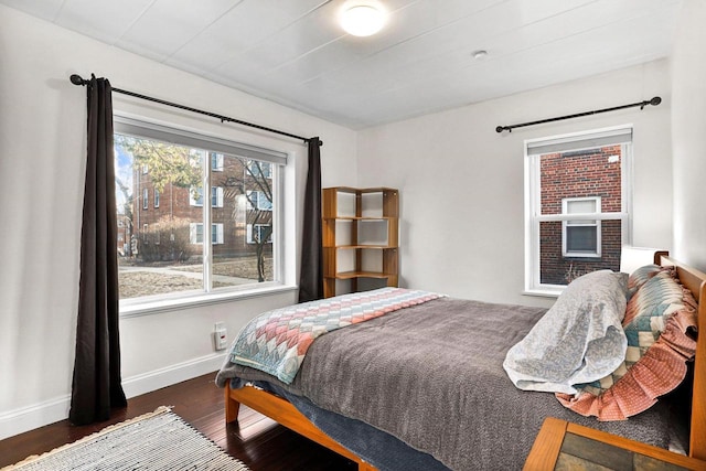 bedroom with baseboards, wood finished floors, and a fireplace