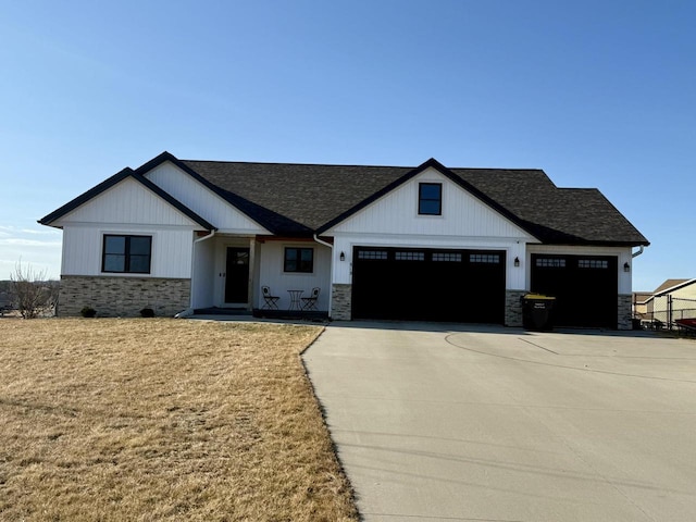 view of front of home with driveway, a garage, stone siding, and roof with shingles