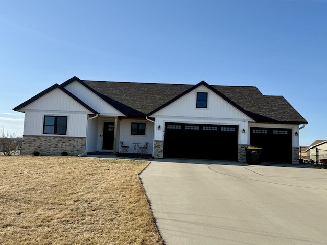 view of front of house with a garage, stone siding, concrete driveway, and a front yard