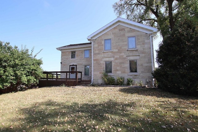 rear view of house with stone siding, a lawn, and a deck