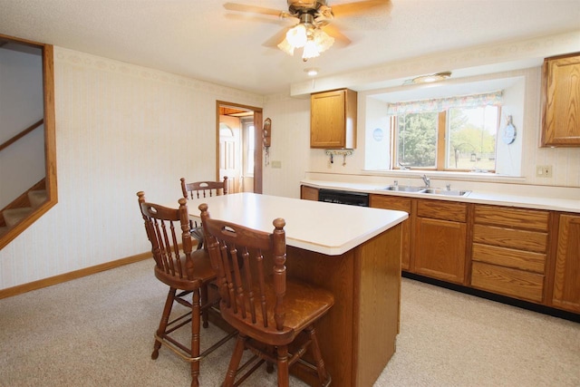 kitchen with a sink, a kitchen breakfast bar, black dishwasher, a center island, and wallpapered walls