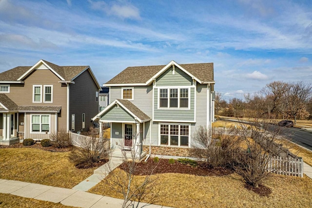 view of front of property featuring stone siding, roof with shingles, a porch, and fence