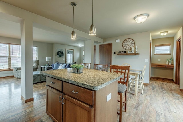 kitchen with a kitchen breakfast bar, light wood-type flooring, a wealth of natural light, and a kitchen island