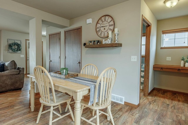 dining space with visible vents, baseboards, and wood finished floors