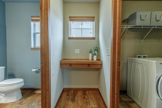 laundry area with washer / dryer, wood finished floors, a healthy amount of sunlight, and laundry area