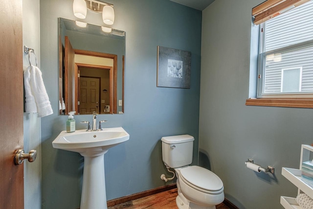 bathroom with a sink, baseboards, toilet, and wood finished floors