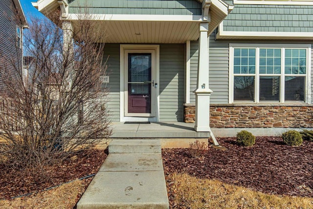 doorway to property with a porch and stone siding