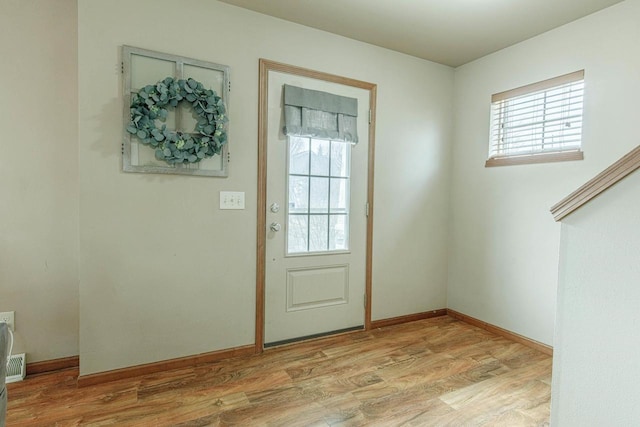 doorway to outside with baseboards and light wood finished floors