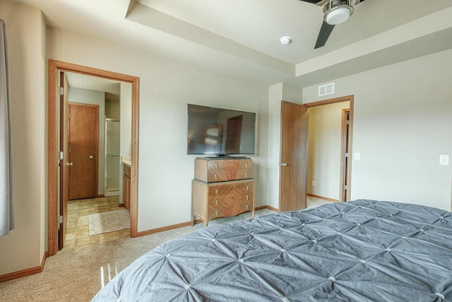 bedroom with light carpet, visible vents, a raised ceiling, and baseboards