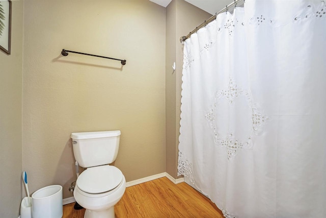 full bath with a shower with curtain, baseboards, toilet, and wood finished floors