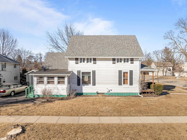 colonial home with a front lawn and a shingled roof