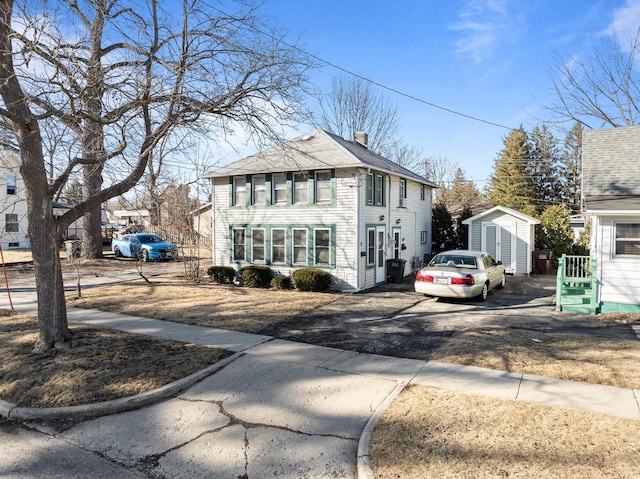 exterior space featuring an outdoor structure, driveway, a shed, and a chimney