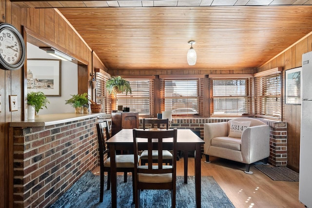 dining space featuring a wealth of natural light, wood walls, wood ceiling, and wood finished floors