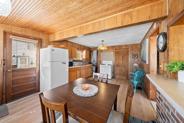 dining area with light wood-style flooring, wood ceiling, and wood walls