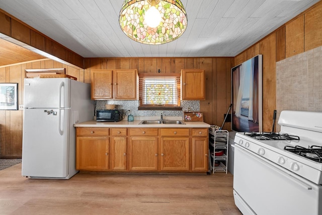 kitchen with light wood-type flooring, a sink, white appliances, wood walls, and light countertops