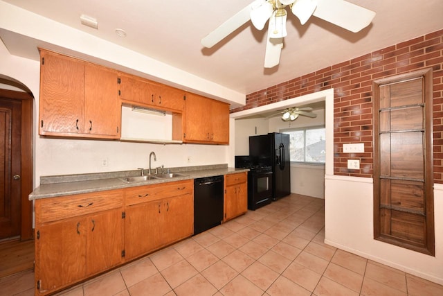 kitchen with brown cabinetry, a ceiling fan, brick wall, a sink, and black appliances