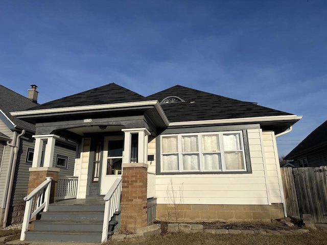 view of front of property featuring roof with shingles, covered porch, and fence