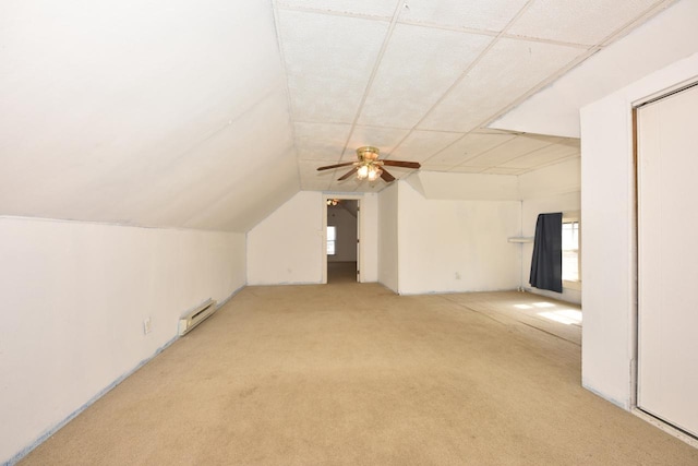 additional living space with a baseboard heating unit, plenty of natural light, light colored carpet, and lofted ceiling