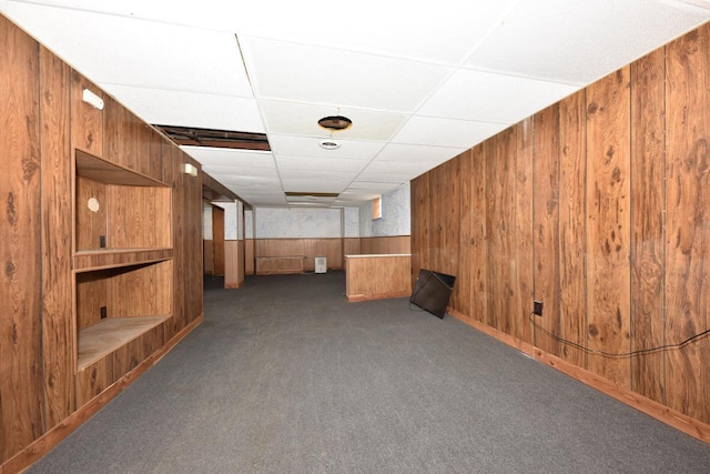 interior space with wooden walls, carpet flooring, and a paneled ceiling