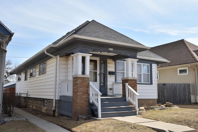 bungalow-style home with roof with shingles and fence