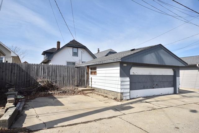 view of side of property featuring an outbuilding, a shingled roof, and fence