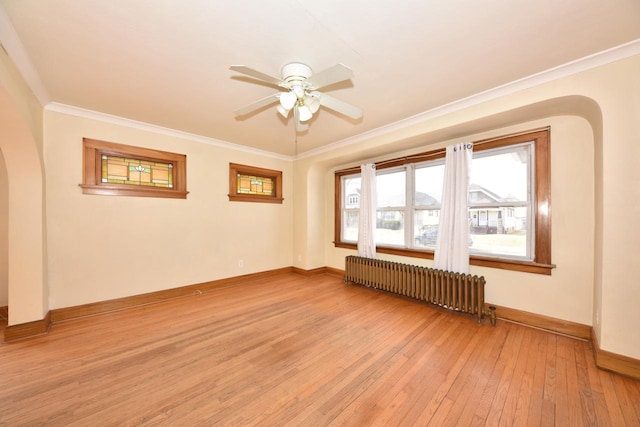 unfurnished room featuring arched walkways, light wood-style flooring, radiator, and crown molding