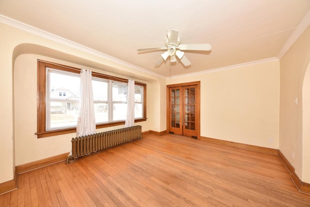 empty room featuring light wood-style flooring, radiator heating unit, arched walkways, crown molding, and baseboards