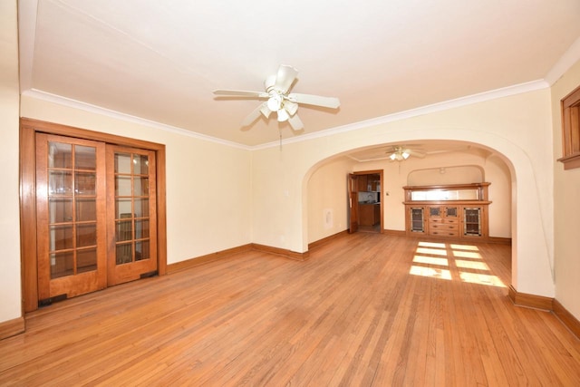 unfurnished room with light wood-style flooring, a ceiling fan, ornamental molding, arched walkways, and baseboards