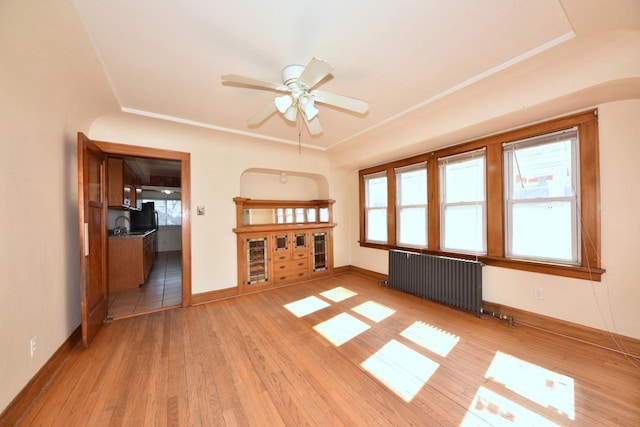 unfurnished living room featuring ceiling fan, radiator, light wood-type flooring, and baseboards