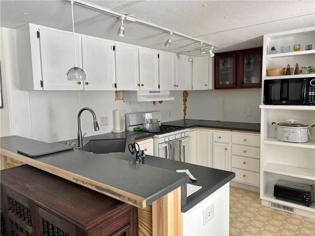 kitchen featuring dark countertops, gas range gas stove, light floors, and black microwave