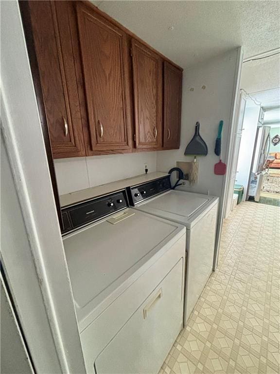 laundry area with a textured ceiling, cabinet space, light floors, and washer and clothes dryer