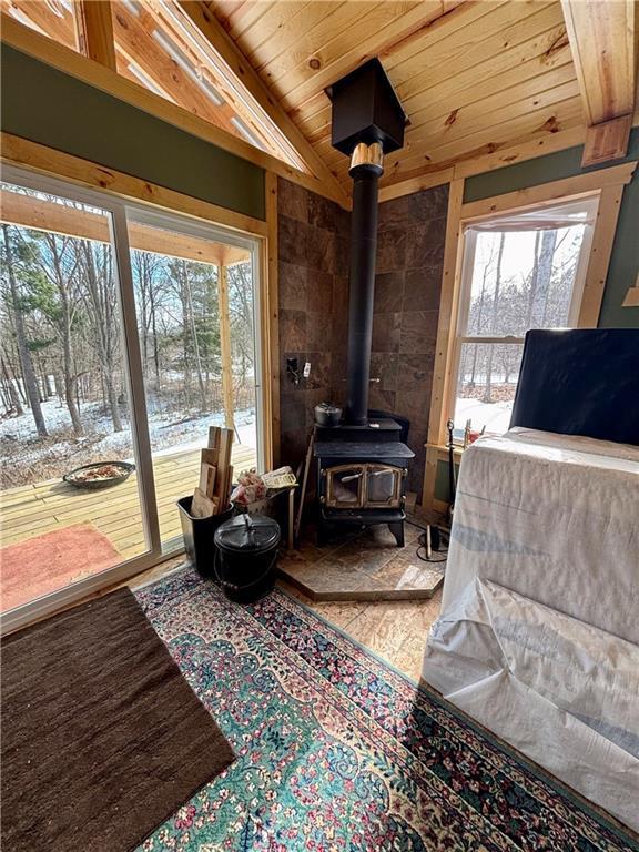 sitting room featuring vaulted ceiling, a wood stove, and wood ceiling