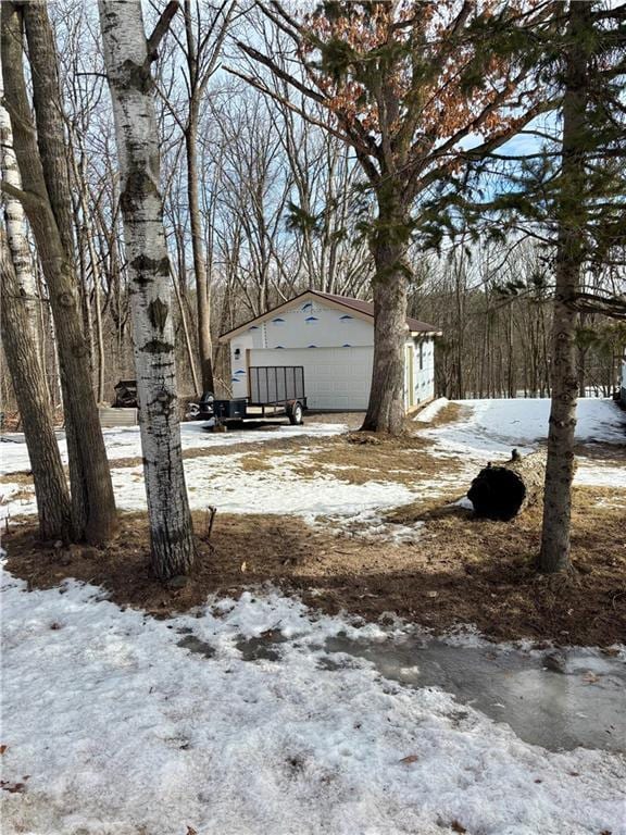 snowy yard featuring an outdoor structure and a garage