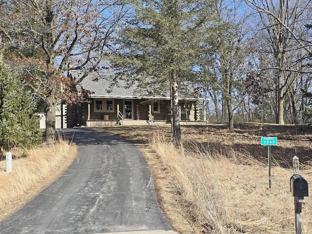 log home featuring aphalt driveway, a porch, and roof with shingles