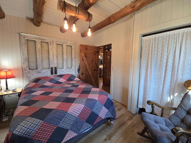 bedroom with beam ceiling and wood finished floors