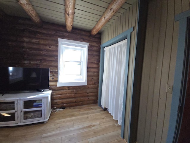 unfurnished living room with beamed ceiling and wood finished floors