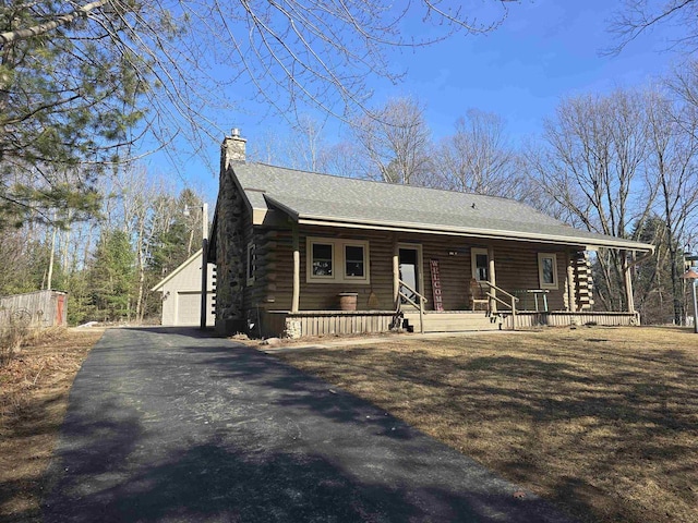 log home featuring a porch, log siding, an outbuilding, and a chimney