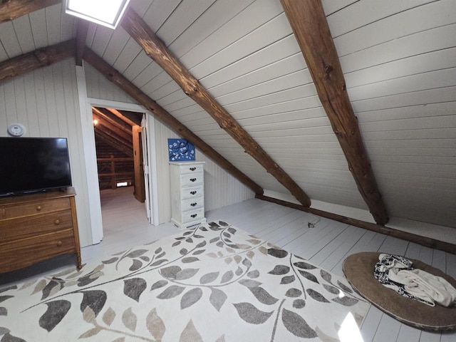 additional living space featuring light wood finished floors, wooden walls, and lofted ceiling with beams