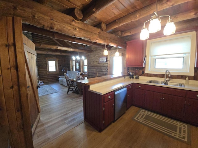 kitchen featuring dark wood finished floors, light countertops, stainless steel dishwasher, rustic walls, and a sink