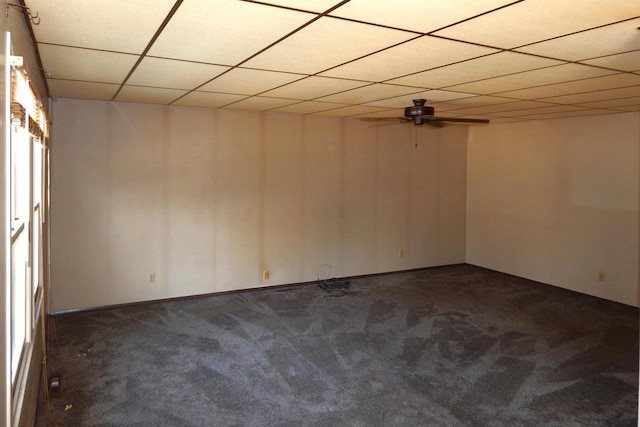 unfurnished room with a drop ceiling, dark carpet, and ceiling fan