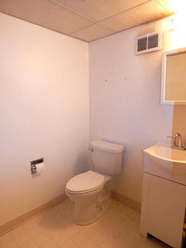 half bathroom featuring tile patterned floors, visible vents, toilet, baseboards, and a paneled ceiling