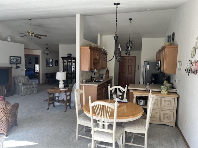 kitchen with light colored carpet, light countertops, lofted ceiling, freestanding refrigerator, and a sink