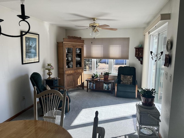 living area featuring ceiling fan, baseboards, and carpet