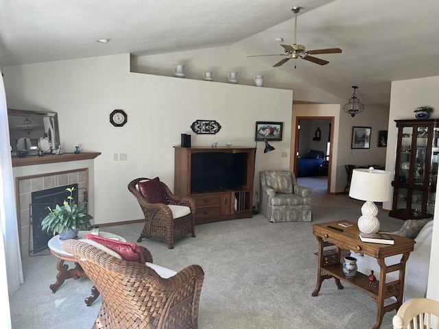 living area with carpet floors, ceiling fan, a fireplace, and vaulted ceiling