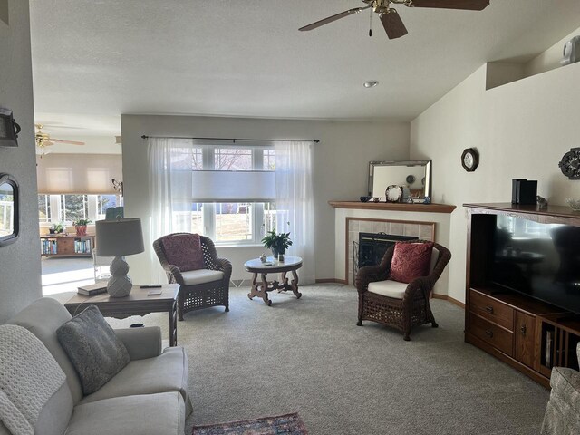 carpeted living area featuring a ceiling fan, baseboards, and a tile fireplace