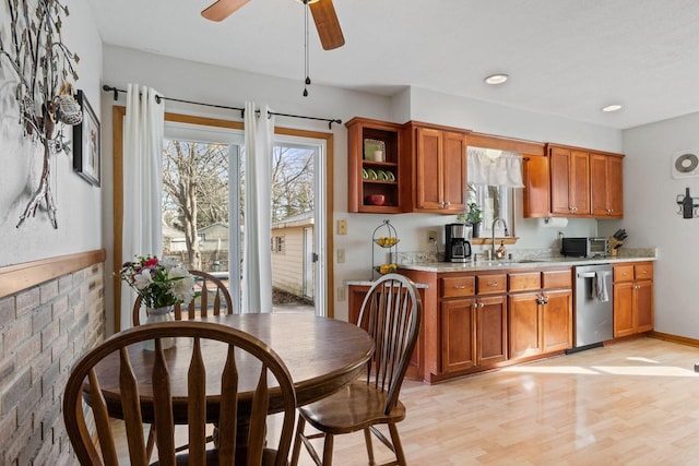 kitchen with dishwasher, brown cabinets, light wood finished floors, and a sink