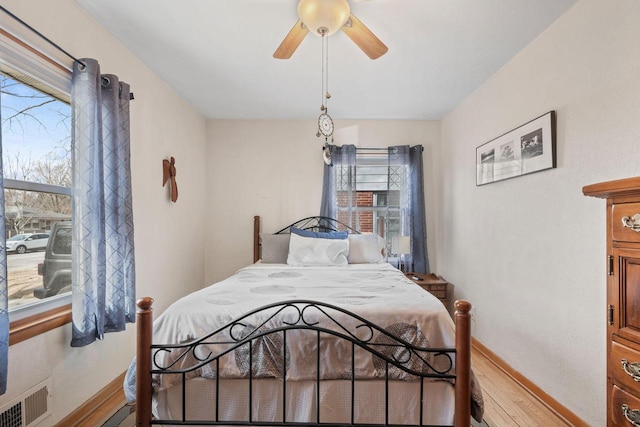 bedroom featuring visible vents, a ceiling fan, baseboards, and wood finished floors