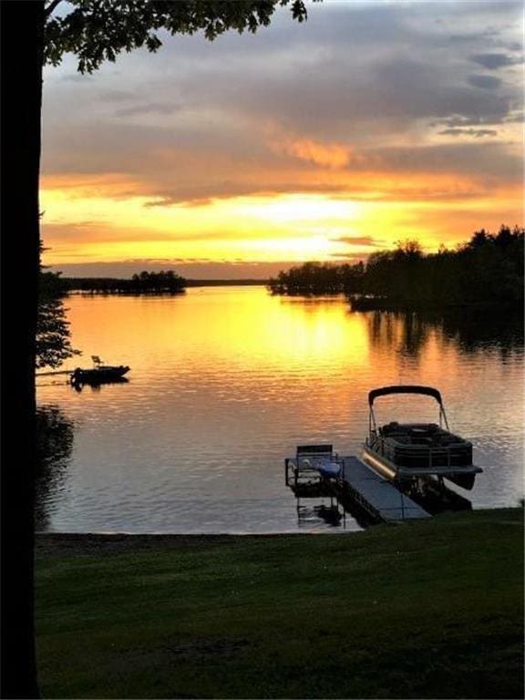 view of dock featuring a yard, a water view, and boat lift