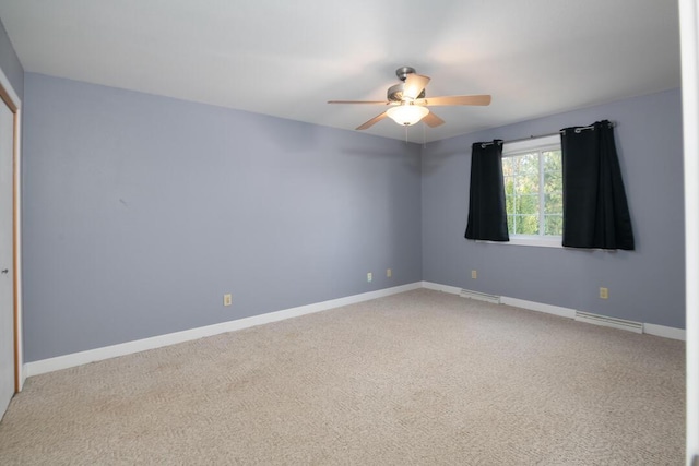 carpeted empty room with visible vents, a ceiling fan, and baseboards