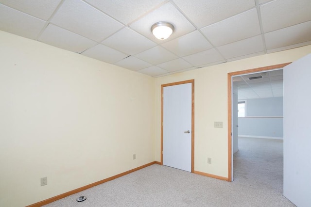 spare room with visible vents, baseboards, a drop ceiling, and light carpet